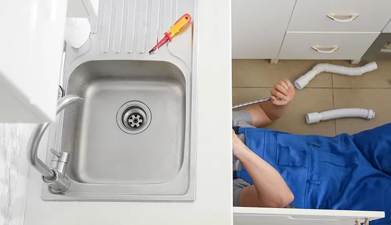 A plumber installs a kitchen faucet and sink