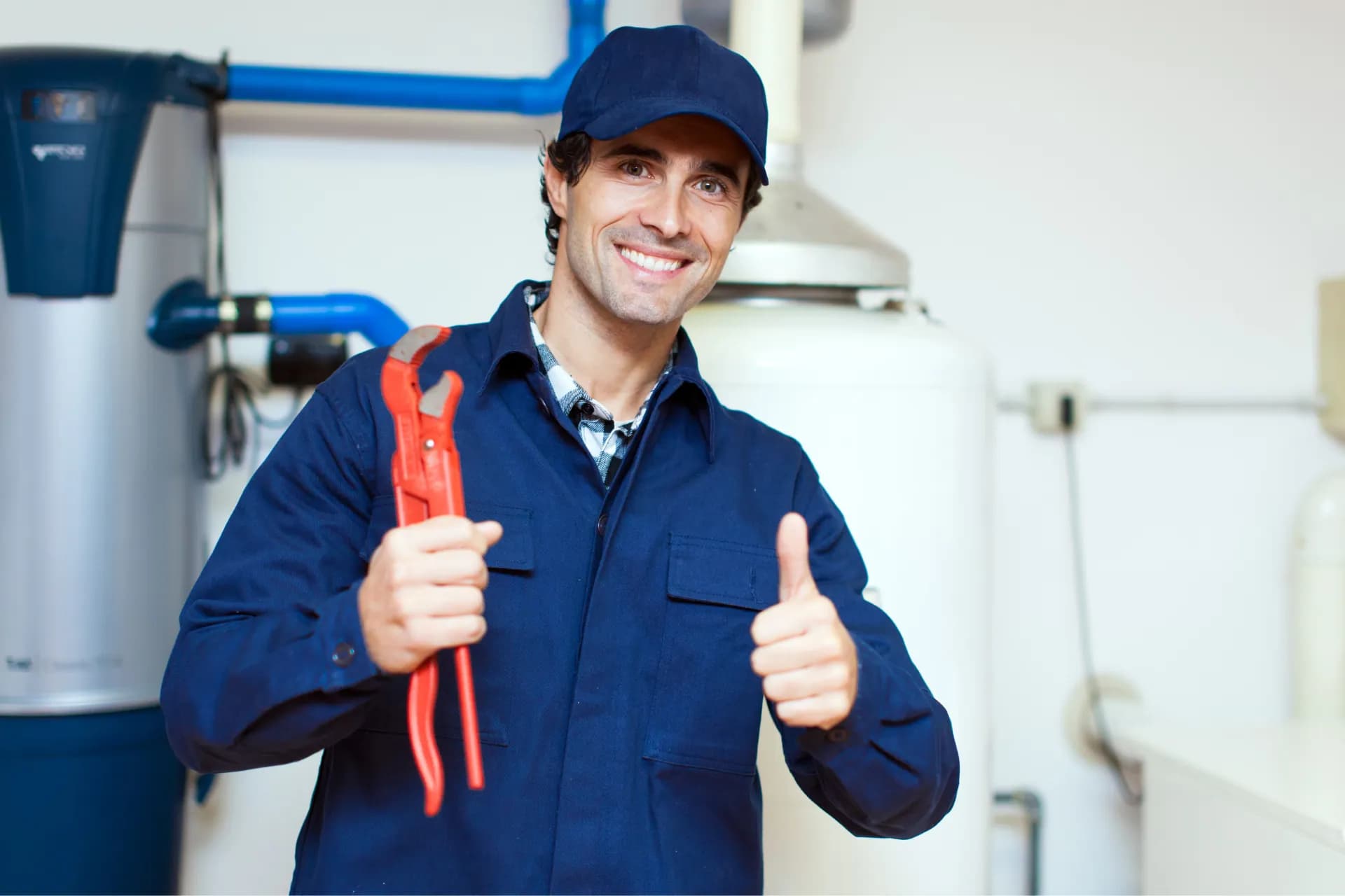 a plumber, holding a wrench, smiling and flashing a thumbs up