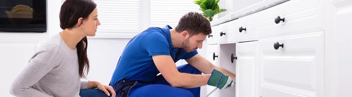 Woman watching a professional plumber use rooter service to clear clogged drain