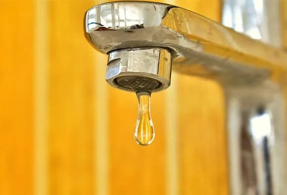 Closeup of a faucet with a drop of water
