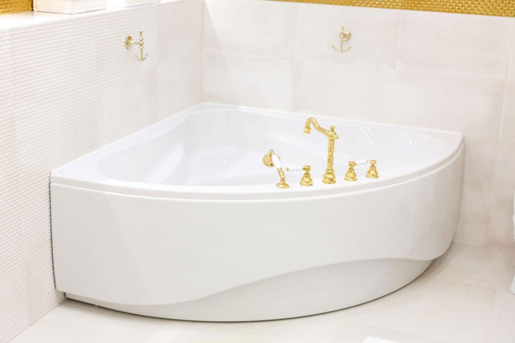 A corner bathtub with golden faucets