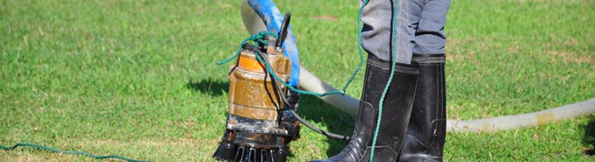 A cropped image of a man in boots cleaning a sump pump in the yard after learning how to clean a sump pump