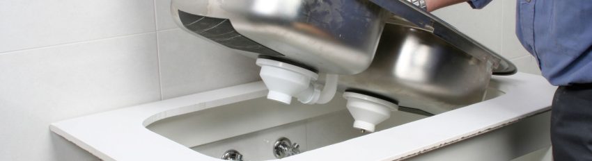 A person installing a double sink in a kitchen