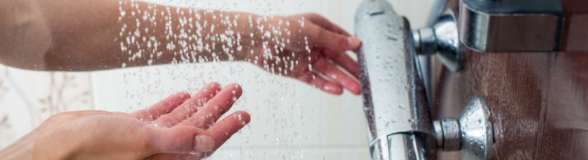 A person testing the temperature of the water in a shower