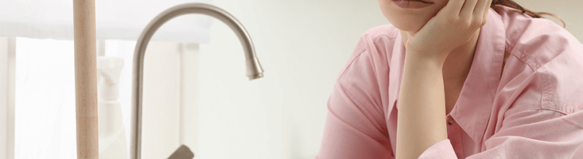 A woman waiting for her sink to drain after using a plunger