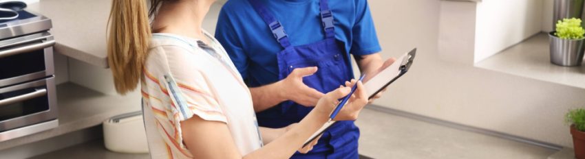 A woman talking to a plumber as they review a clipboard together